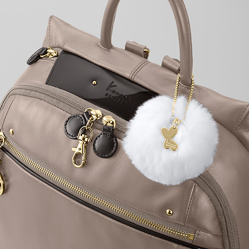 Two types of leather—soft and patent—let you travel with panache. The real-fur lucky charm is a light-hearted accent.